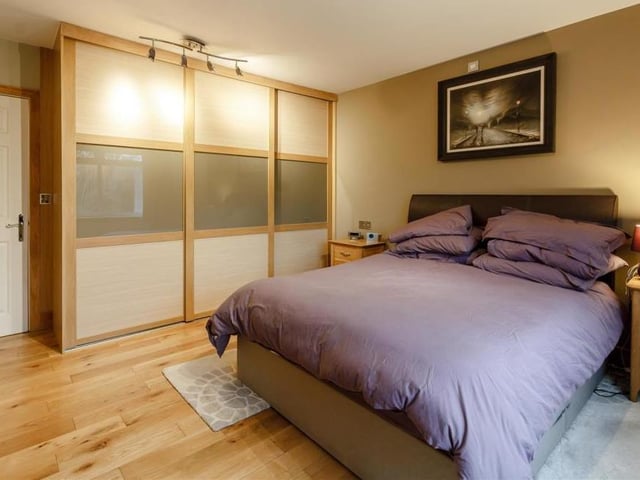 The delightful master bedroom boasts a substantial range of contemporary fitted wardrobes, with hanging rails, shelving and 'soft close' sliding doors. The floor is solid oak, the window looks out on to the back garden, and another sliding door leads to a large en suite bathroom.