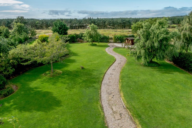 A meandering pathway leads through the lawn to the rear where there is a decked terrace and summerhouse.