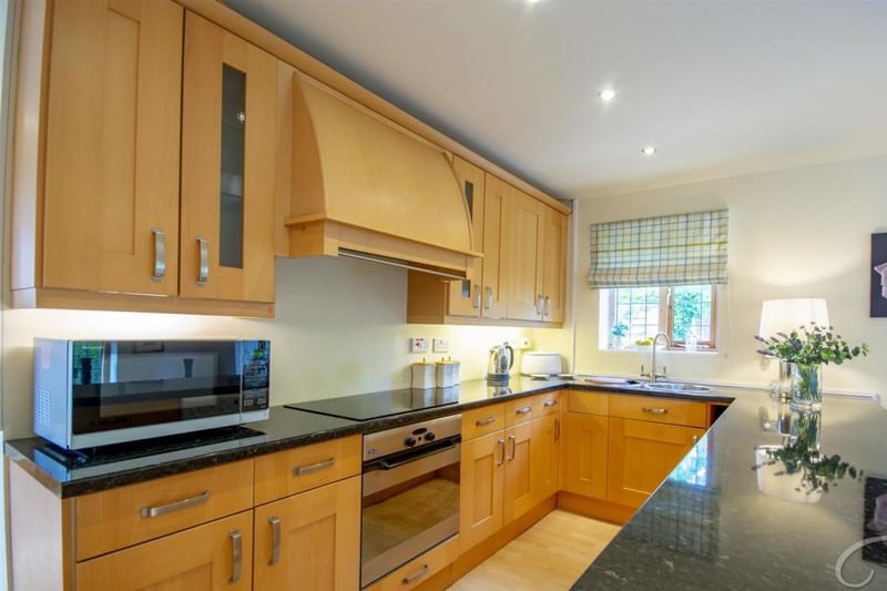 The kitchen inside the annexe. It includes shaker-style cabinets and units, a work surface, integral dishwasher and an inset sink with a mixer tap above.
