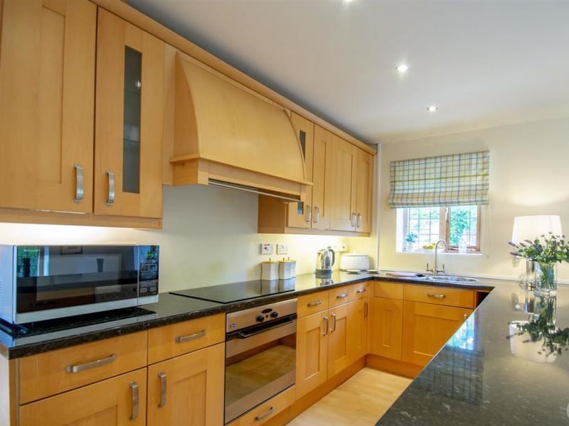 The kitchen inside the annexe. It includes shaker-style cabinets and units, a work surface, integral dishwasher and an inset sink with a mixer tap above.
