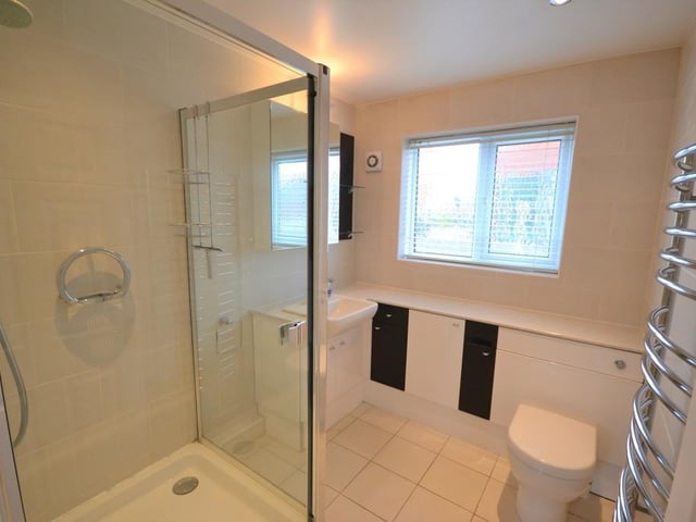 Family shower room - An attractively presented shower incorporating a large shower enclosure with mains fed shower and glass panels, a vanity unit with cupboards and inset wash basin, low level flush wc, chrome heated towel rail, extractor fan, inset down lighting, UPVC double glazed obscure window and complimented with stylish ceramic wall and floor tiles.