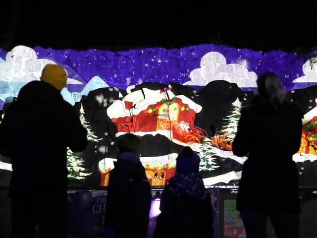 Members of the public view an animation projected onto a rock face at the launch of Edinburgh Zoo's Christmas Nights.