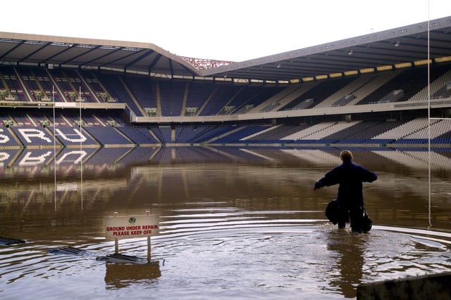 Murrayfield Stadium's head groundsperson Heather MacKinnon wades through water following flooding due to heavy rainfall in the city, 27 April 2000.