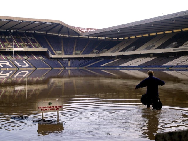Murrayfield Stadium's head groundsperson Heather MacKinnon wades through water following flooding due to heavy rainfall in the city, 27 April 2000.