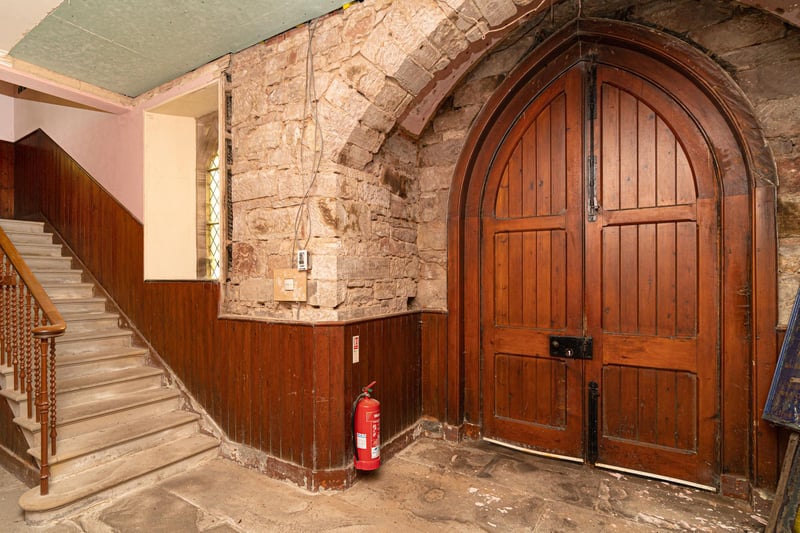 Beautiful arched wooden doorway sits adjacent to the stairs leading up to the first floor.