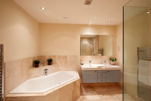 There are five bathrooms throughout the property, including this modern suite complete with dual sinks, a walk in shower, and spacious corner bath.