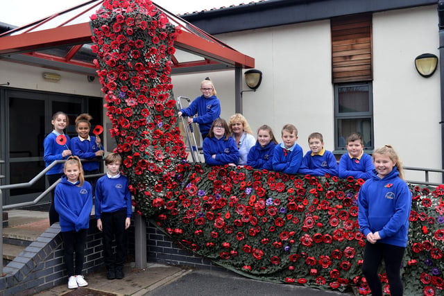 Dunn Street Primary school Nursery Nurse Karen Ramshaw (centre) with a selection of pupils alongside their poppy display in 2018.