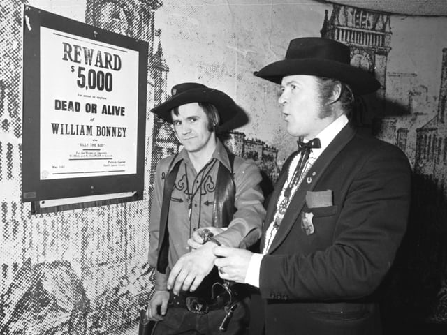 Dressed as cowboys and Western characters Dick Gilmour (as Marshall Dillon) 'arrests' Jim Webb (as Billy the Kid) ina Paisley Road West club, Glasgow, November 1980.