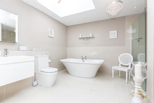 The en-suite bathroom features a white WC, basin, freestanding bath, large walk-in shower enclosure, heated towel rail, tiled flooring, mirror cabinet, and a Velux window.