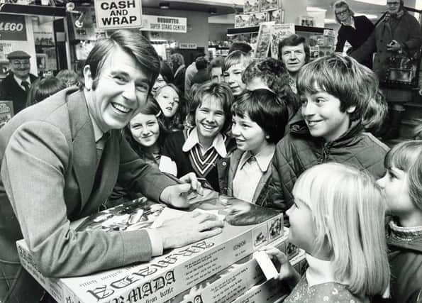 Television presenter Leslie Crowther pictured at Redgates store, Sheffield, surrounded by a crowd of smiling youngsters, November 22, 1975