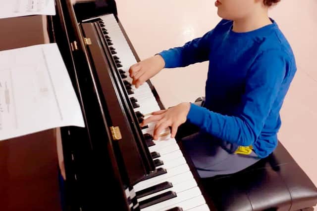 Young musician Lennie Street playing the piano donated to Paces School