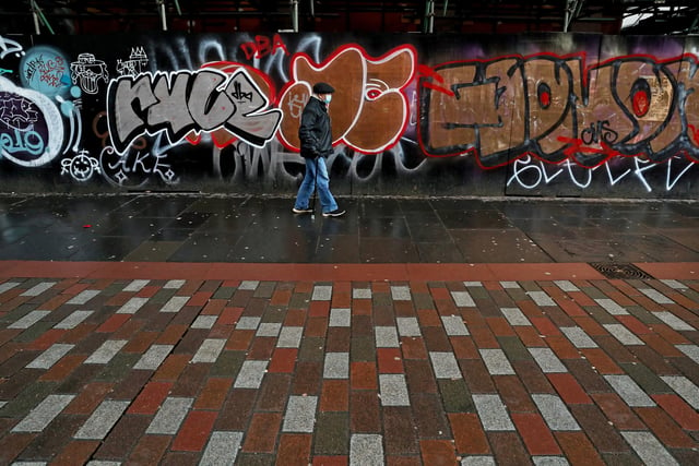 A man wearing a face mask walks past graffiti on Argyle Street in Glasgow city centre