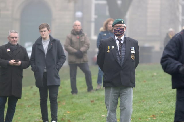 A veteran looks on, with others socially-distanced behind
