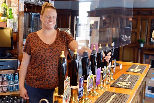 Chesterfield Arms landlady Emma Clarke behind the screen at the bar.