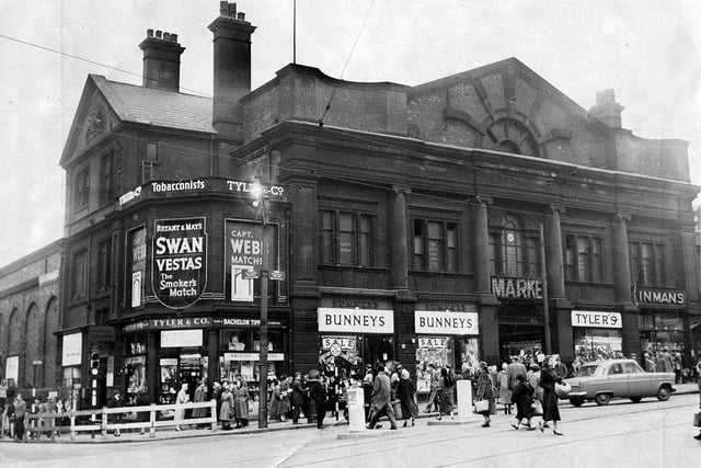 The Norfolk Market Hall, Haymarket, opened on Christmas Eve 1851 and closed in 1959, was built on the site of the famous old Tontine Inn (1785-1849). 
From right to left the shops are G.E. Inman, pastry cooks,  Tyler's, bootmakers,  Bunneys (Hosiery) Ltd., drapers, and the popular tobacconists, Tyler and Co. on the corner with Exchange Street.

 