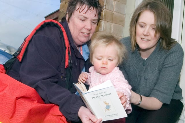 Joanne Hinchliffe with her baby daughter, Alice, receiving a copy of her first Imagination Library book, provided by Dolly Parton's Dollywood Foundation,  from Royal Mail postie Alyson Ayrton in February 2008