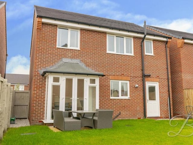 As we step outside again, here is a view of the property from the back garden, which features a lawn and a patio area.