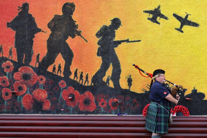 A piper plays in front of Murray Robertsons mural at Grangemouth British Legion during Armed Forces Day