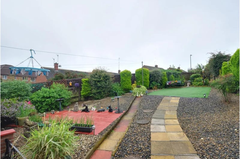 The property is host to a spacious rear garden with artificial lawn, mature trees and patio seating area.