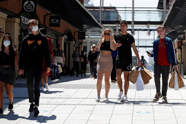 Shoppers, some wearing PPE (personal protective equipment), of a face mask or covering as a precautionary measure against COVID-19, walk past recently re-opened shops at Gunwharf Quays.