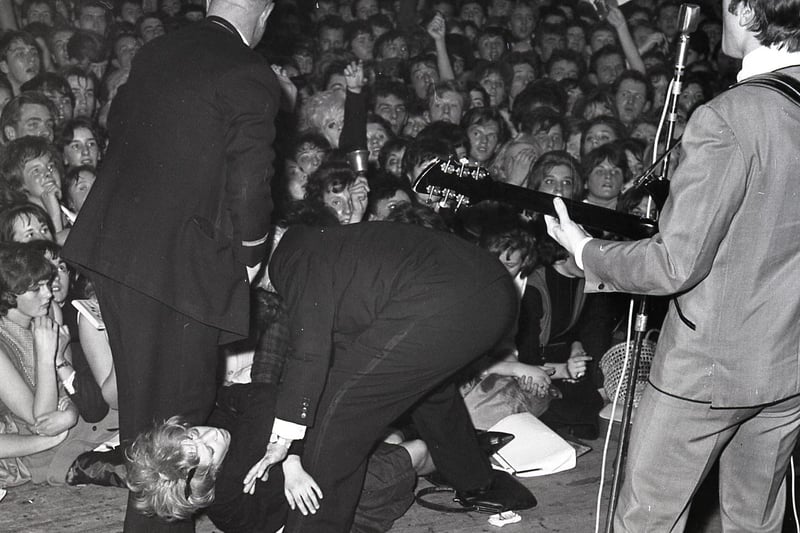 Buxton Advertiser Archive, John Lennon plays on as fainting fans are carried from the audience at Buxton's Pavilion Gardens in 1963