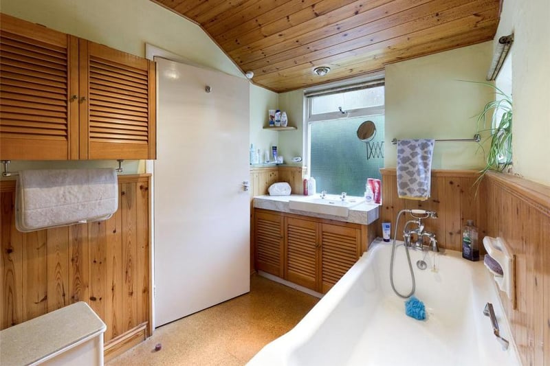 Bathroom - Low level WC, pedestal wash basin and panelled bath with shower head mixer tap; single glazed timber framed window and electric radiator panel.