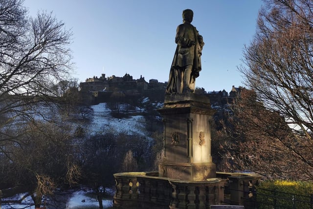 The statue of Scottish poet, Allan Ramsay, basks in some lovely winter sunshine on Princes Street, Edinburgh, with Edinburgh Castle sitting majestically in the background
