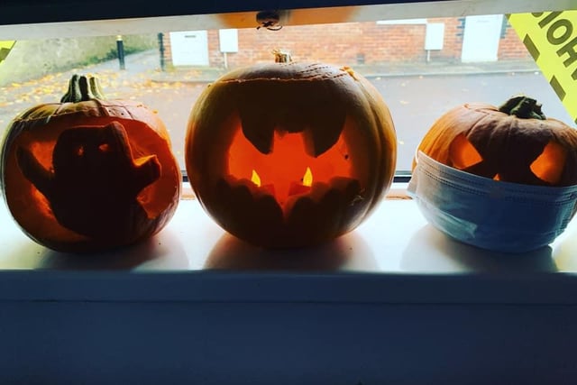 A Halloween window display by Ashley Watson - a ghost, bat and pumpkin complete with face covering.