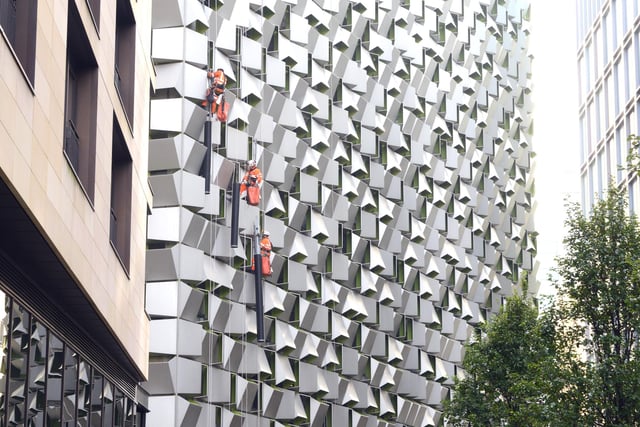 Workmen in orange boiler suits line up along Charles Street car park - known to one and all as the cheese grater because of its striking cladding