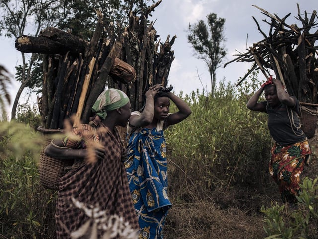 Displaced women carry firewood toward the internally displaced persons (IDP) camp of Bijombo - The photograph was taken at the exact spot where a woman and three girls were killed by militiamen returning from collecting firewood.
