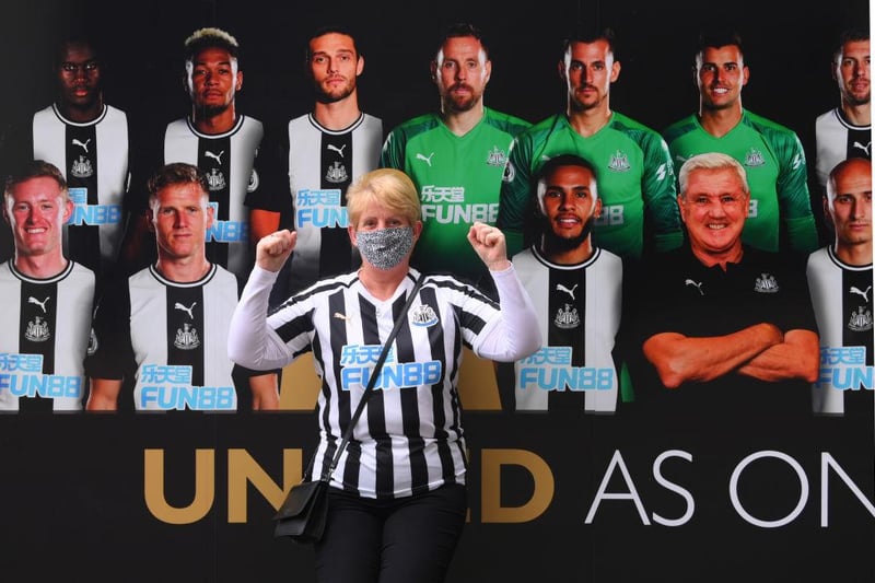 A Newcastle United fan poses for a picture in front of a board resembling the team photo.