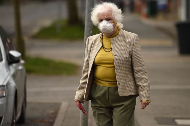 An elderly woman wearing a protective face mask leaves a newsagents (Photo by Oli SCARFF / AFP) (Photo by OLI SCARFF/AFP via Getty Images)