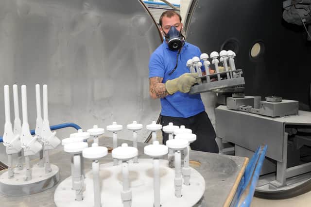 Dale Burbeary, coating operative at JRI Orthopaedics takes implants out of a vacuum plasma spray system which applies hydroxyapatite coating.