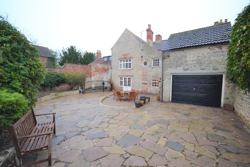 Large wrought iron double gates open to a private fully enclosed rear garden with driveway access to a two storey building with garage door access.