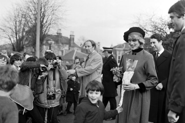 Princess Diana and Prince Charles visit Craigroyston in Edinburgh, March 1983. Photographers capture the moment when the Princess of Wales is handed some lucky white heather by nine-year-old Malcolm Smith.