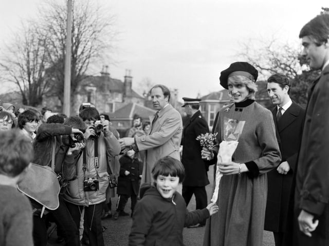 Princess Diana and Prince Charles visit Craigroyston in Edinburgh, March 1983. Photographers capture the moment when the Princess of Wales is handed some lucky white heather by nine-year-old Malcolm Smith.