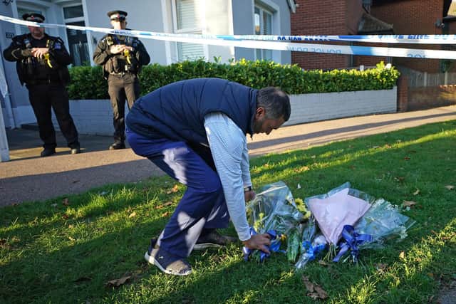 A man lays flowers at the scene near the Belfairs Methodist Church in Eastwood Road North, Leigh-on-Sea, Essex, where Conservative MP Sir David Amess has died after he was stabbed several times at a constituency surgery. A man has been arrested and officers are not looking for anyone else. Picture date: Friday October 15, 2021. PA Photo. See PA story POLICE MP. Photo credit should read: Yui Mok/PA Wire 