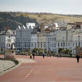 Dogs walkers and cyclists take advantage of the fine weather on the promenade in Llandudno, (Photo by OLI SCARFF/AFP via Getty Images)