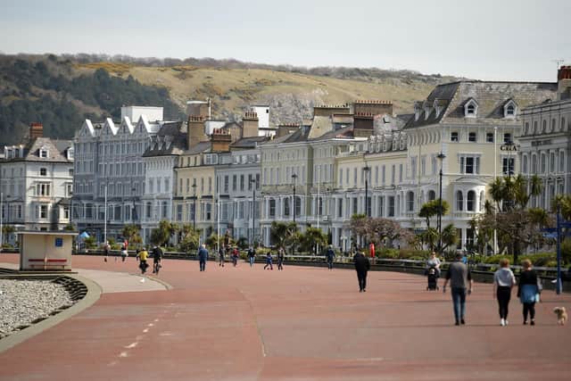 Dogs walkers and cyclists take advantage of the fine weather on the promenade in Llandudno, (Photo by OLI SCARFF/AFP via Getty Images)