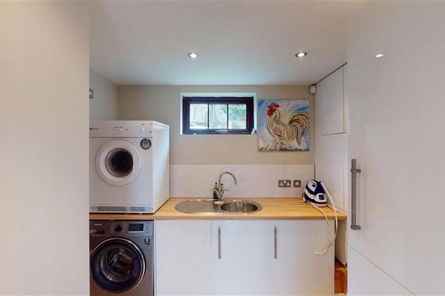 The utility room gloss cupboards and a full length built-in storage cupboard and ample space for an additional fridge.