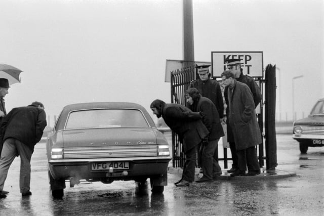 Police keep an eye on the NUM official picket as they try to stop cars entering Seafield colliery in Fife during the miners' strike of February 1974.