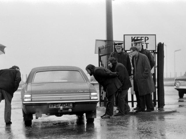 Police keep an eye on the NUM official picket as they try to stop cars entering Seafield colliery in Fife during the miners' strike of February 1974.