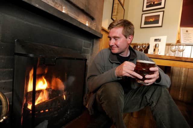 Warming up next to a pub's log fire with a pint. Picture: Steve Ellis.