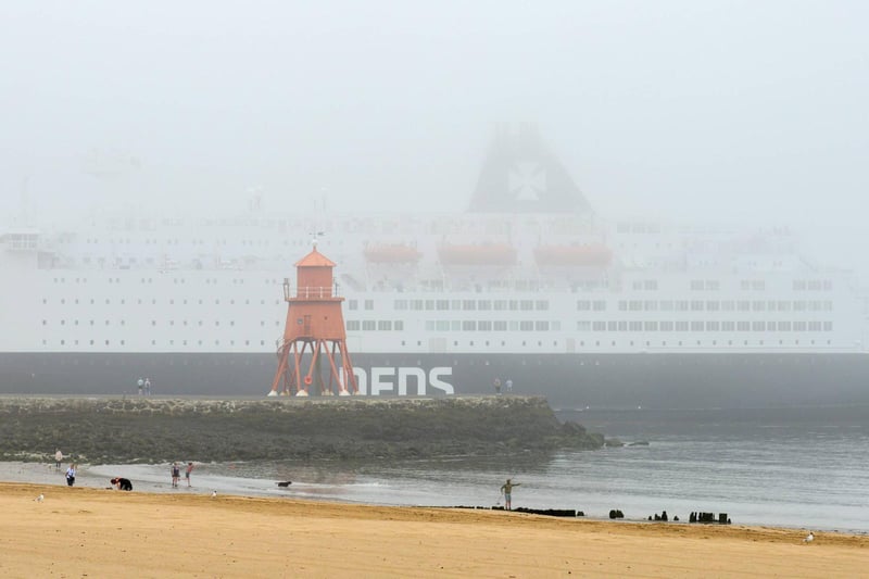 Walkers look on as the DFDS ferry passes by in the fog.