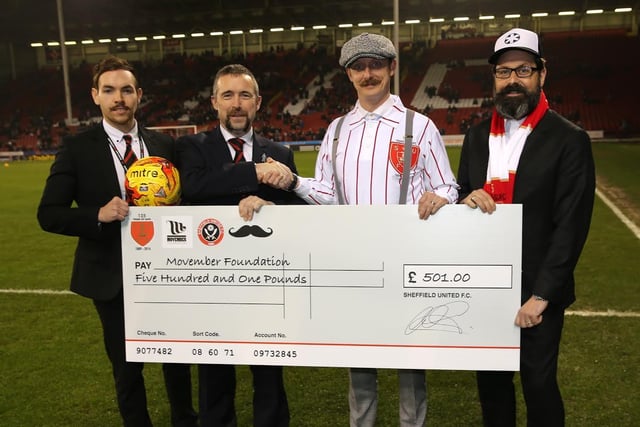A cheque on behalf of the Movember Foundation was collected by Jonathan Davies, owner of Sheffield barbers Savills Barbers, and bespoke British Fashion Designer, John Lancaster.
Also pictured handing over the cheque in 2014, and sporting their own Movember growths, are the Blades’ Managing Director Mal Brannigan (inside left) and Commercial Executive, Liam Robinson (left)