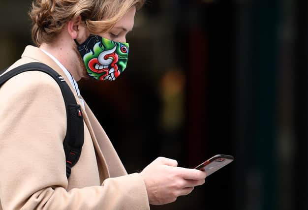A man wearing dragon-themed face mask or covering due to the COVID-19 pandemic (Photo by OLI SCARFF/AFP via Getty Images)