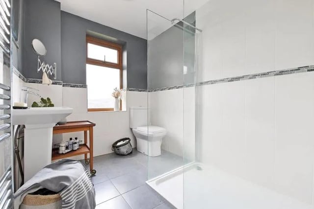The fabulous shower room has a large walk in shower cubicle with glass screening, a wash basin, WC, stylish tiling, including a tiled floor, and a heated towel rail.