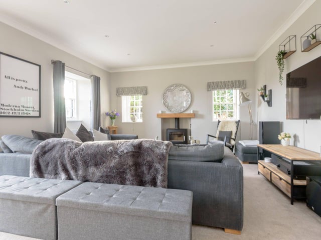 The spacious living room has a wood-burning stove and doors leading out the garden