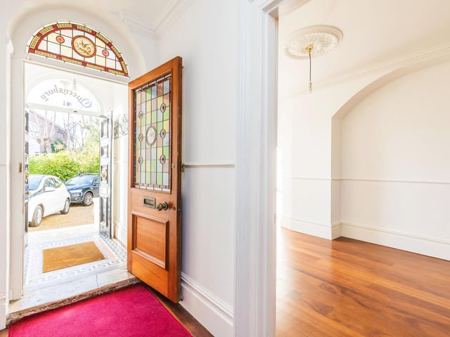 The hallway has a feature archway, ceiling coving, ceiling roses, staircase rising to all floors, Lincrusta style wallpaper to lower sections.