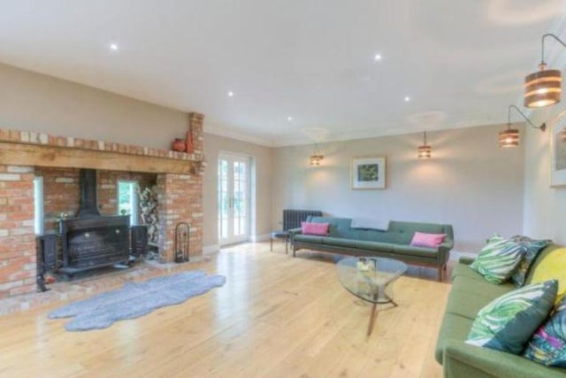 The sitting room features a fireplace and wood burning stove, two sets of French doors lead to the garden and double French doors lead to the dining area.